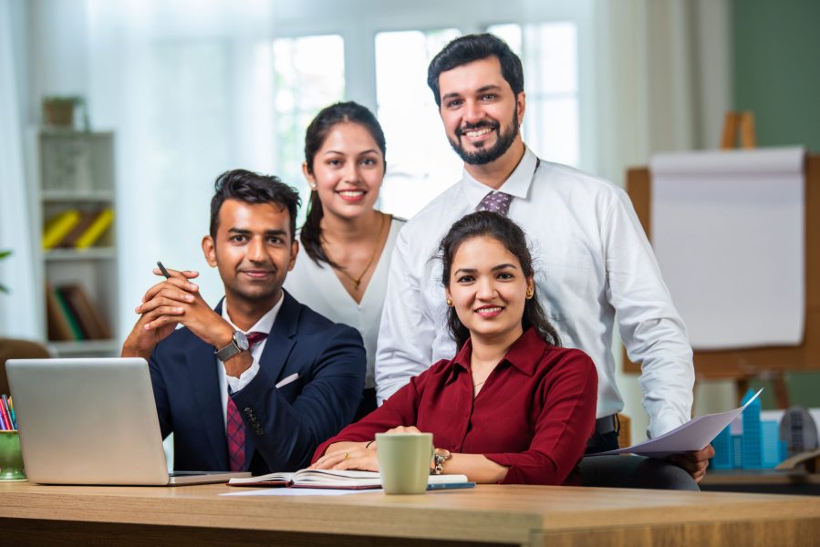 Indian asian young business professionals using laptop on desk discussing strategy